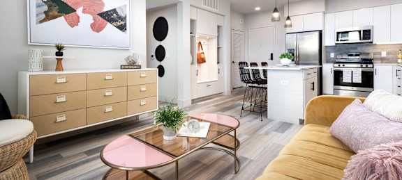 A modern living room with a pink coffee table and a yellow sofa.