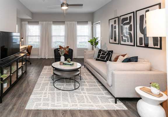 A living room with a grey couch, a white chair, a black table, and a television at Willowest in Lindbergh in Atlanta, Georgia