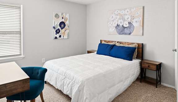 A bedroom with a bed, chair, and painting on the wall.