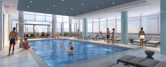 The indoor pool at 3THIRTY3 Apartments, bustling with swimmers and loungers, features expansive windows and a vibrant community atmosphere.