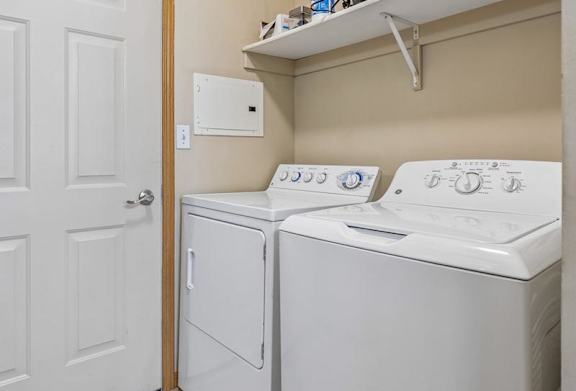 partment laundry room with full-size washer and dryer, shelving, and additional storage space.