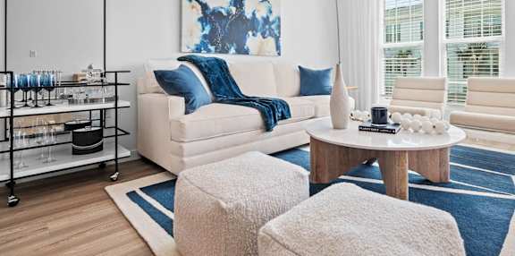 A living room with a white couch, a blue and white rug, and a large painting on the wall
