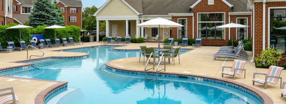 a large swimming pool with chairs and umbrellas in front of a house