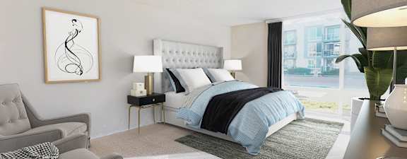 A bedroom with a large bed and a grey armchair.