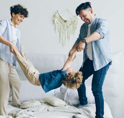 a man and two women are playing with a child on a bed