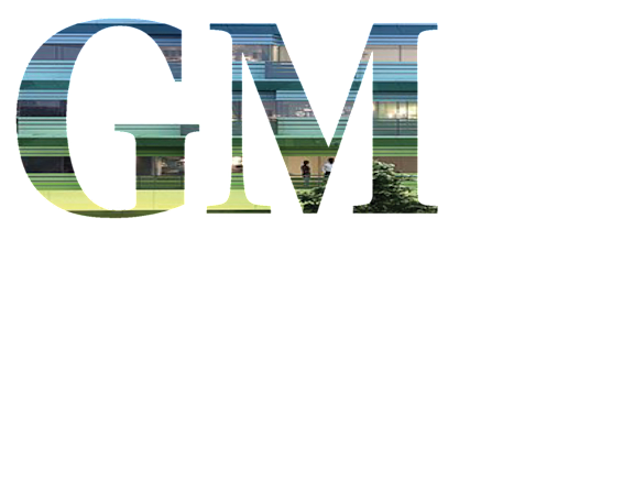 The image shows the letters G, M in different colors with a blurred background of a building.
