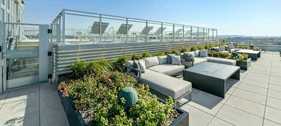 A rooftop patio with a glass railing and furniture.