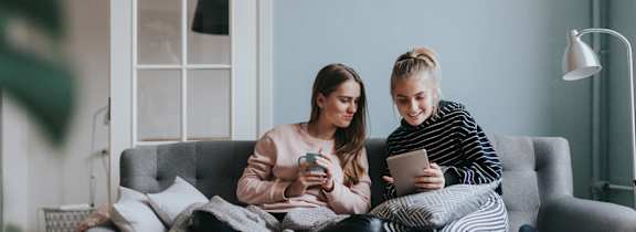 Two girls on a couch looking at their phones