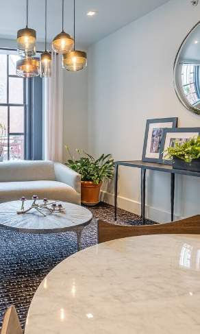 A modern living room with a sofa, a chair, a table, and a mirror on the wall.