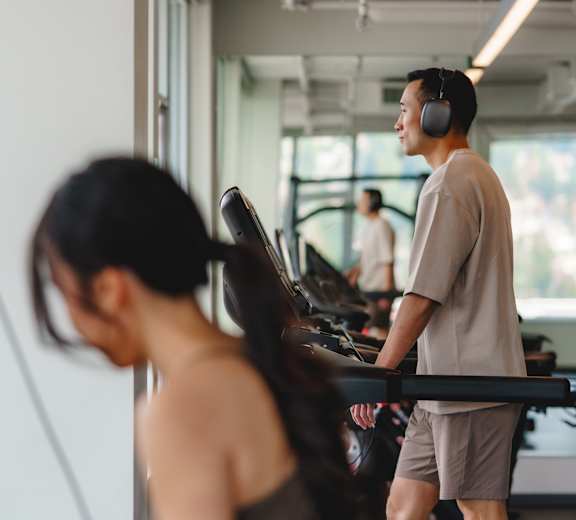 A man and a woman are working out on treadmills in a gym.