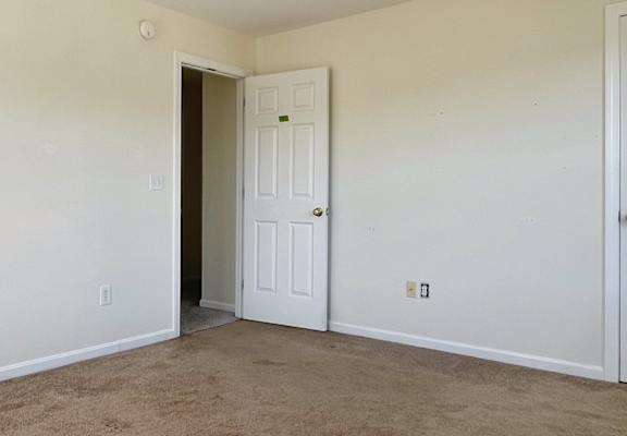 A room with a carpeted floor and two doors.