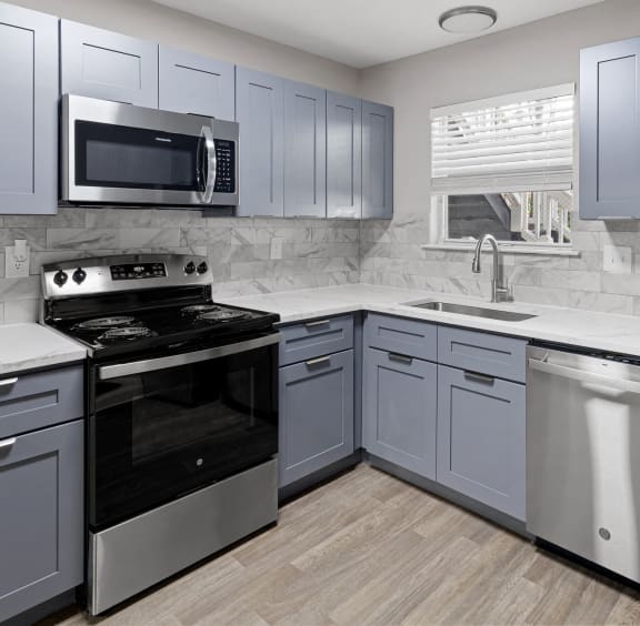 a kitchen with white cabinets and gray appliances