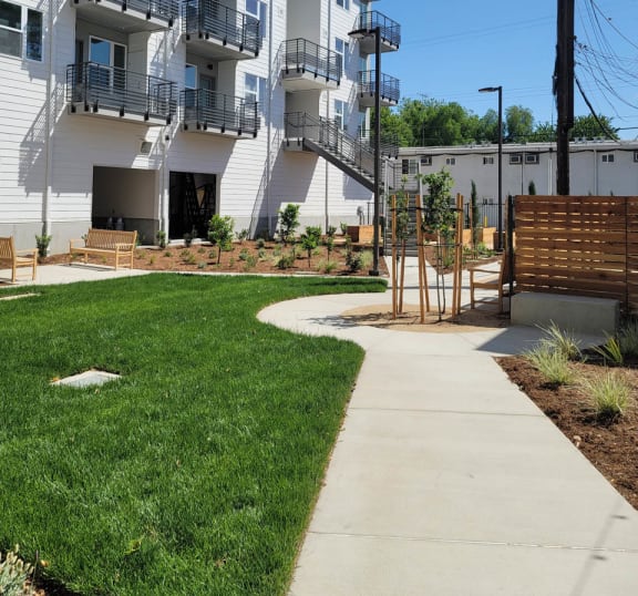 Courtyard at Lavender with large green space, walkways, and 4 story white building.