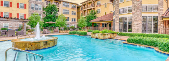 a swimming pool with a fountain and buildings in the background