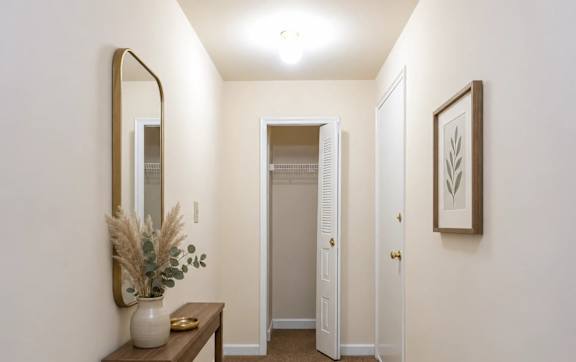 A hallway with a brown carpet and white walls.