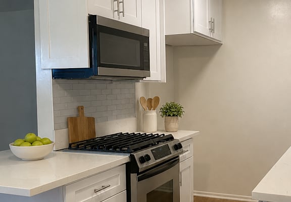 A modern kitchen with white cabinets and a black stove top oven.