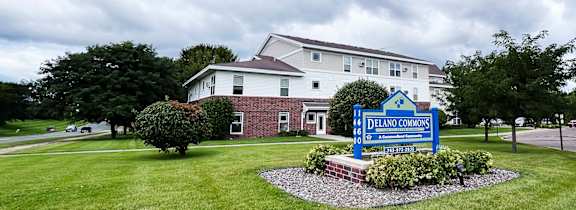 A sign in front of a building that says Delano Commons.