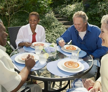 Pair of Older Couples Sitting On Patio Eating Food