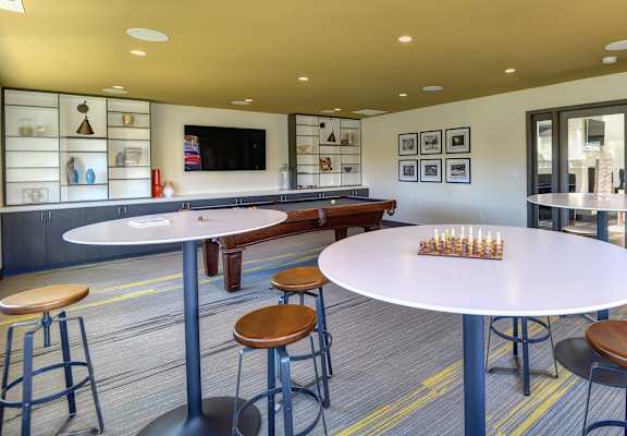 Community Clubhouse Game Room with Round Desk, Stools, Chess Set, Mounted Flatscreen Television at Addison Ranch Apartments, Petaluma, 94954