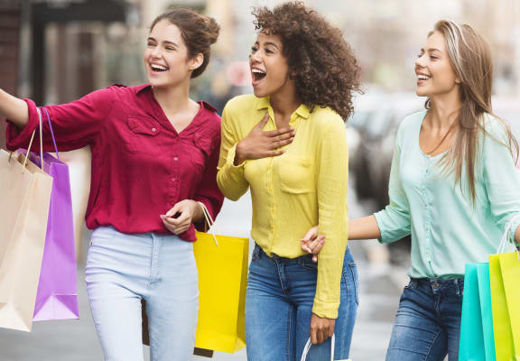 three women walking down the street with shopping bags