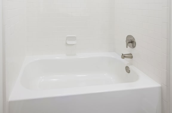 a white bathtub with a shower head in a white bathroom
