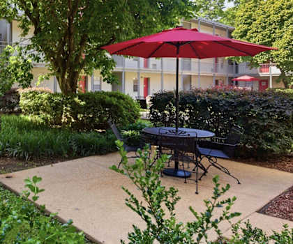 A red umbrella is on a patio table in a courtyard.
