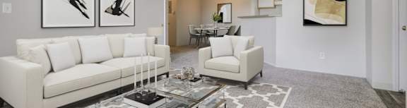 A living room with a white couch, a coffee table, and two framed pictures on the wall.