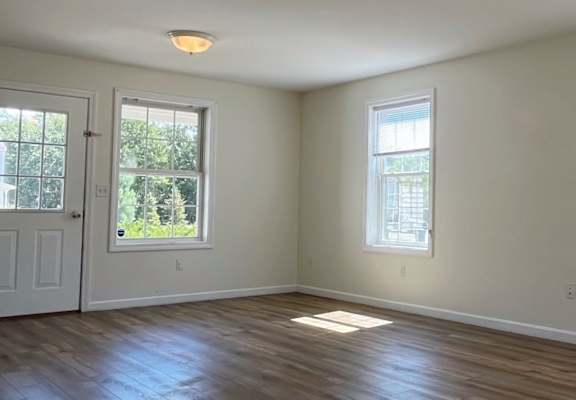 A room with wooden floors and two windows.