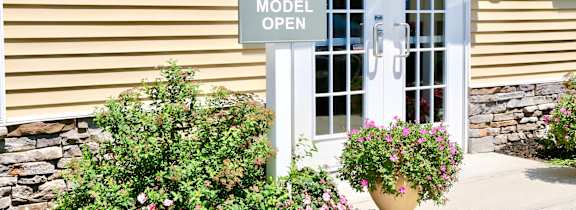 A white door with a sign that says "Model Open" in front of a house.