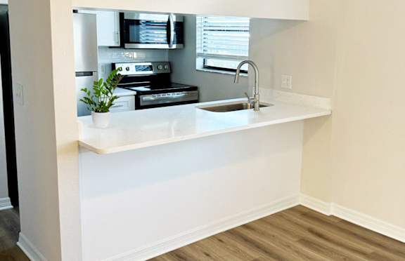 A kitchen with a white countertop and wooden flooring.