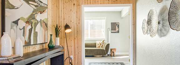 A hallway with a wooden wall and a bench with a mirror above it.