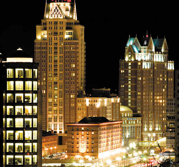 A cityscape at night with three tall buildings illuminated by lights.