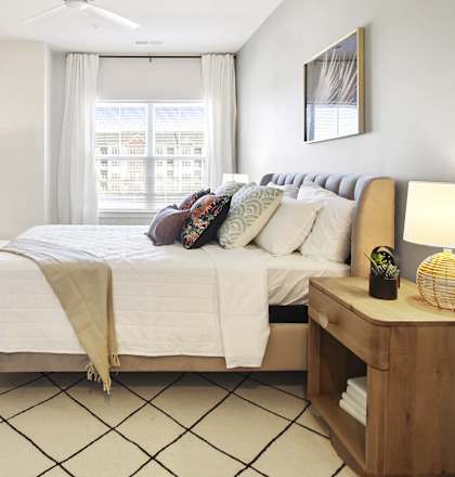A bedroom with a large bed, a mirror, a dresser, and a ceiling fan.