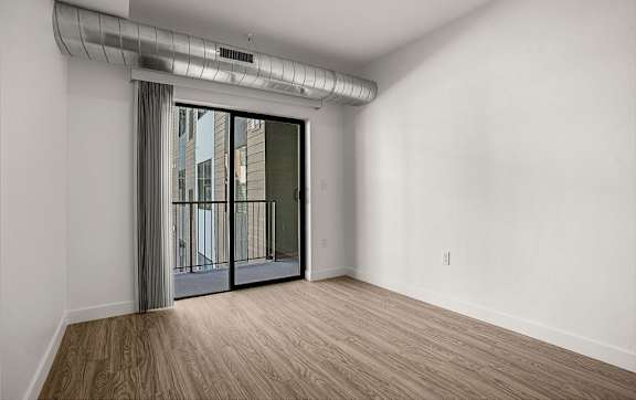 A room with a sliding glass door leading to a balcony.