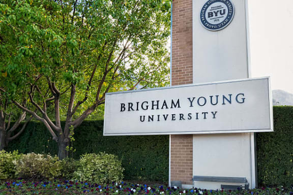 A sign for Brigham Young University is displayed in front of a tree. at The Alloy at Geneva, Vineyard, UT