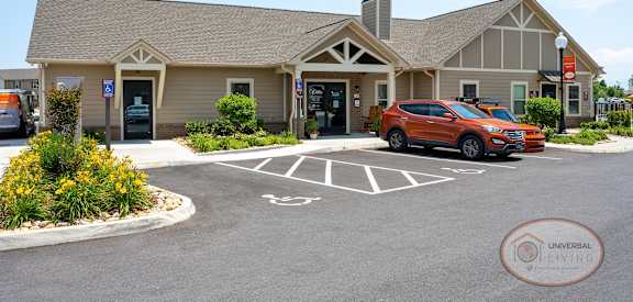 a building with a parking lot and a red car in front of it