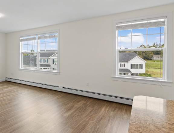 a living room with white walls and wood floors and a door to a house