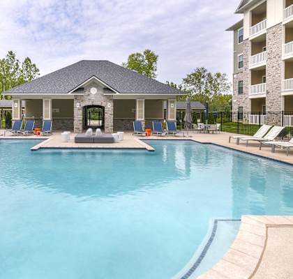 A large swimming pool in front of a building with a gazebo.