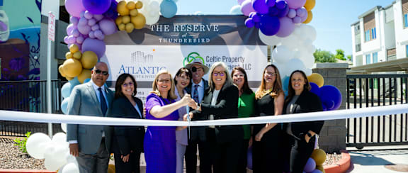 A group of people are gathered for a ribbon cutting ceremony.