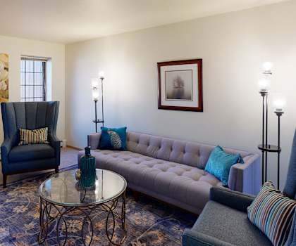A living room at Birchwood Homes with a couch, plush chairs, and coffee tables. 