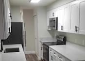 Thumbnail 3 of 24 - a kitchen with white cabinets and a sink and a refrigerator