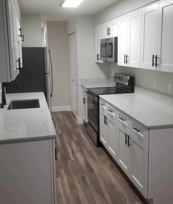 a kitchen with white cabinets and a sink and a refrigerator