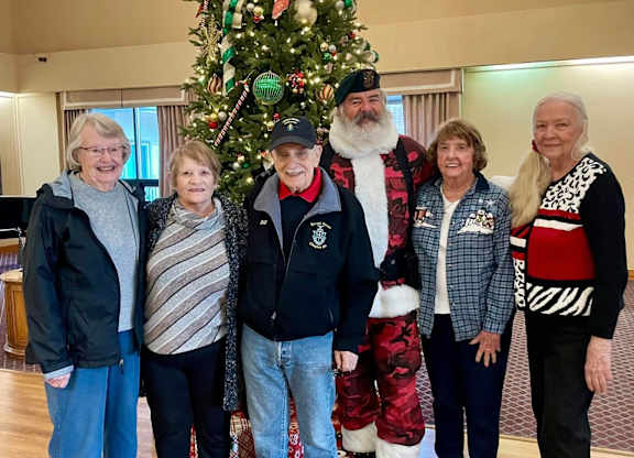 A group of people pose in front of a Christmas tree at River Commons Senior Living, Redding, CA, 96002