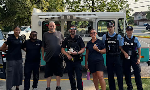 A group of people in uniform stand in front of a white van.