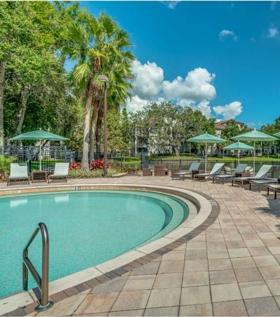 A pool surrounded by lounge chairs and umbrellas.