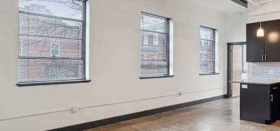 A large empty room with a kitchen area on the right side.
