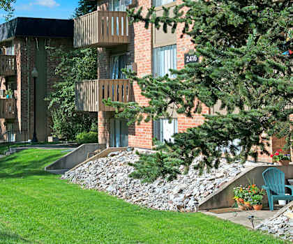 The pathway surrounded by grass and trees leading to the apartment building at Hyde Park Apartments.  