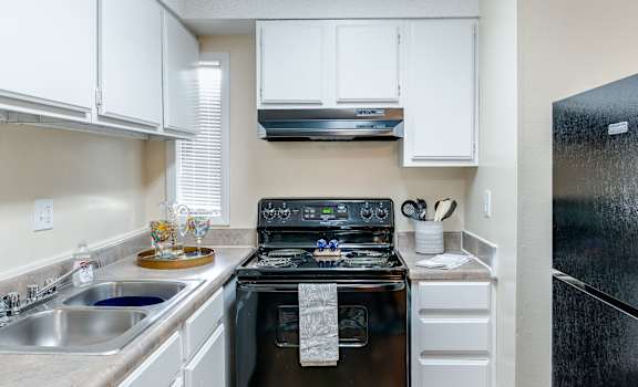 a kitchen with white cabinets and black appliances