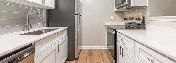 A kitchen with white cabinets and a black refrigerator.