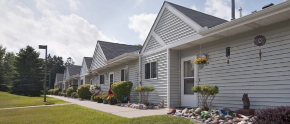 a row of white houses with a sidewalk and landscaping